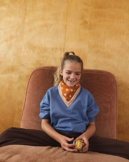 Foulard enfant en coton bio caramel motif fleurs porté par une petite fille