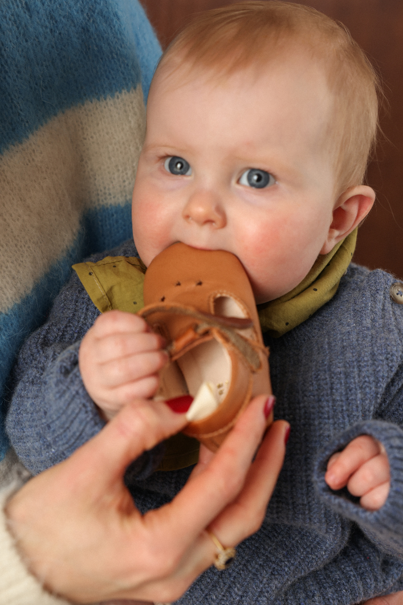 Bébé avec des chaussons en cuir souple écologique à la bouche