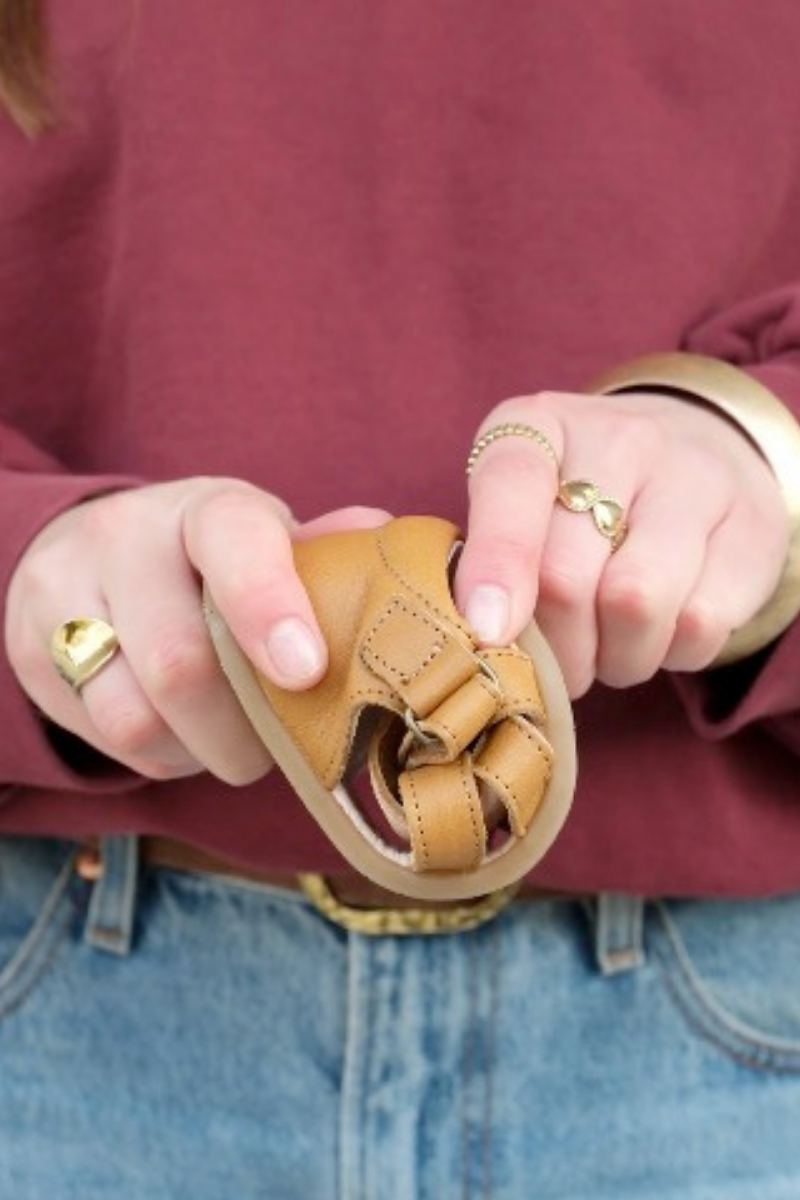 Chaussures enfants en cuir souple Lazare plié en deux dans une main, test de souplesse
