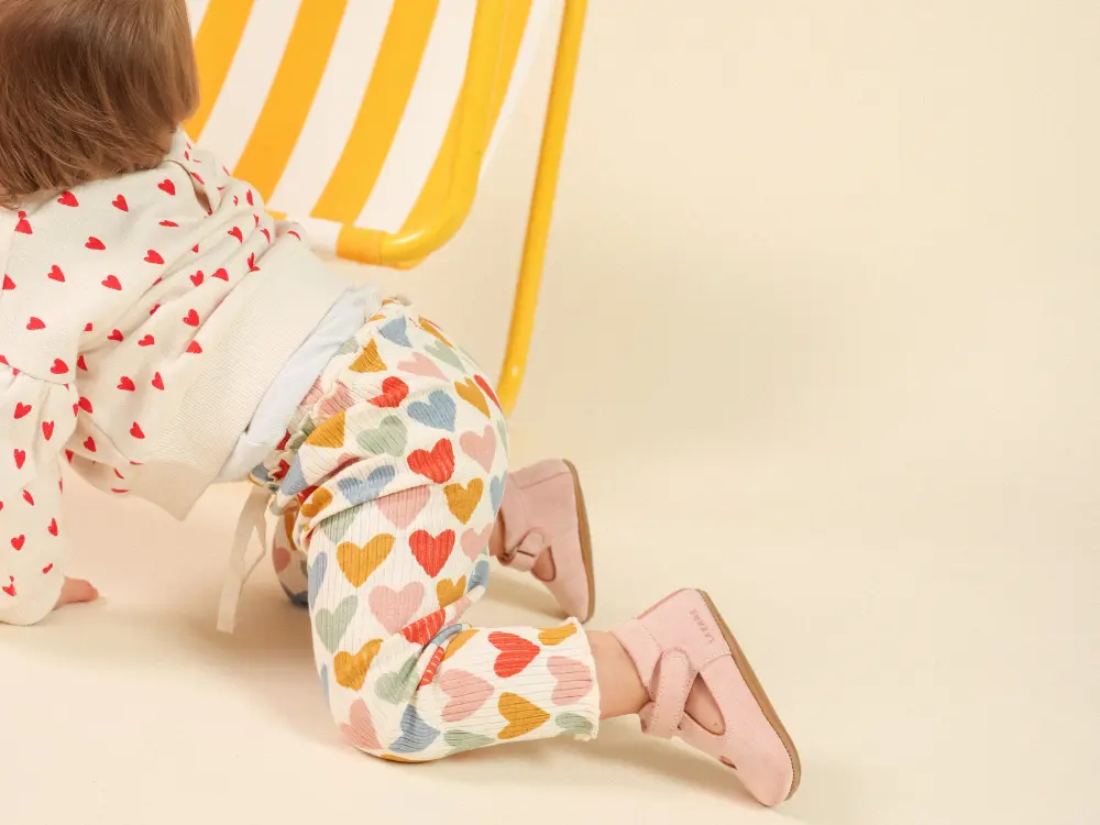 Bébé en motricité libre sur tapis d’éveil, jambes en mouvement