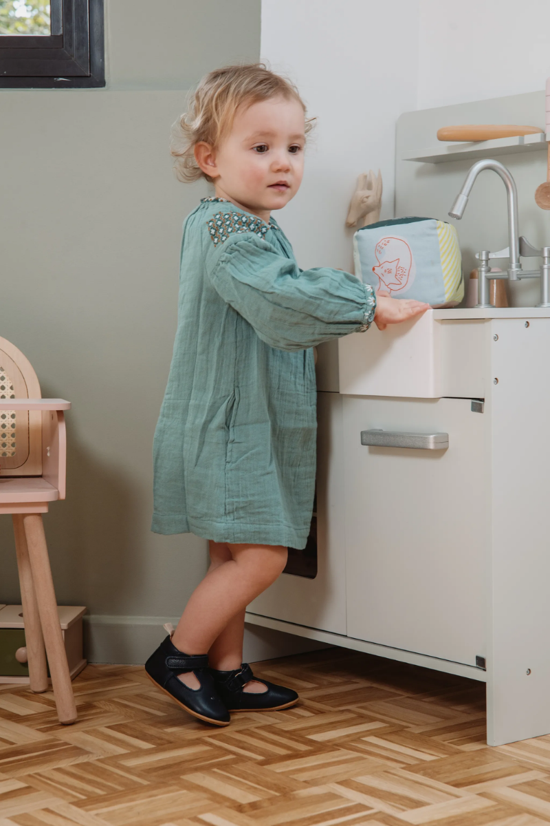 Bébé faisant ses premiers pas dans la chambre en chaussons en cuir souple Lazare