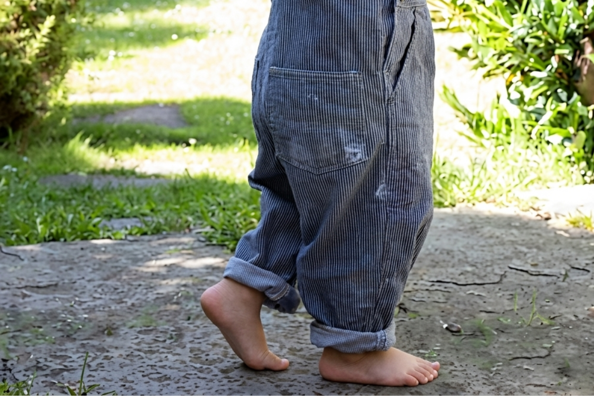 Enfant marchant pieds nus dans l'herbe pour favoriser le déroulé du pied