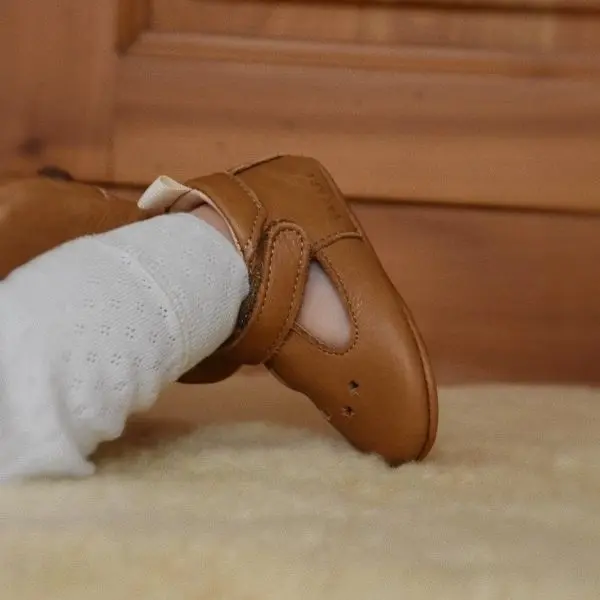 Chaussons en cuir souple cesar marron portant par un bébé allongé sur le ventre