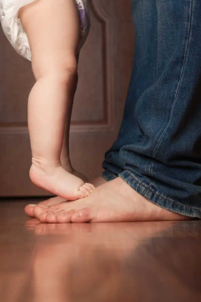 bébé qui marche sur les pieds de son parent