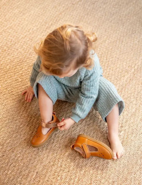 une enfant qui enfile ses chaussures pia marron