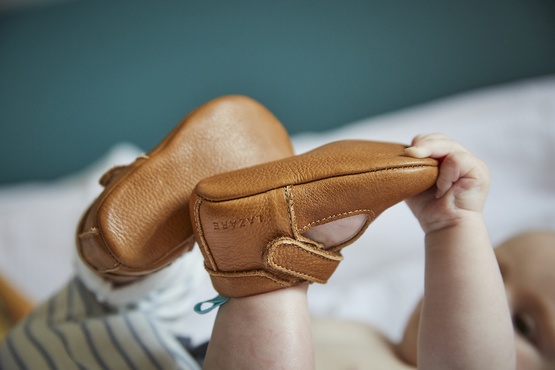 bébé portant des chaussons en cuir souple César marron attrapant ses pieds