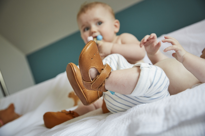 jambes de bébé portant des chaussons souples en cuir César marron