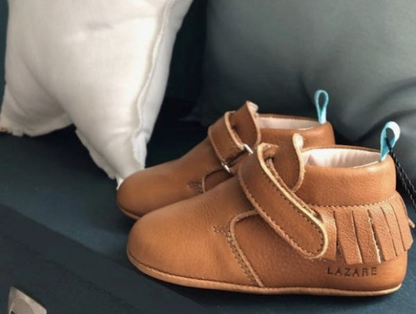 chaussons bébé en cuir souple marron à franges sur canapé