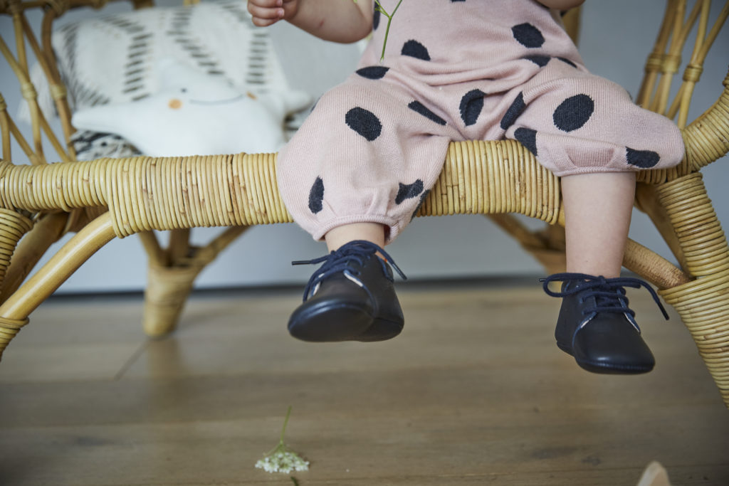 enfant assis sur fauteuil portant les chaussons en cuir souple bleu marine du modèle colombe