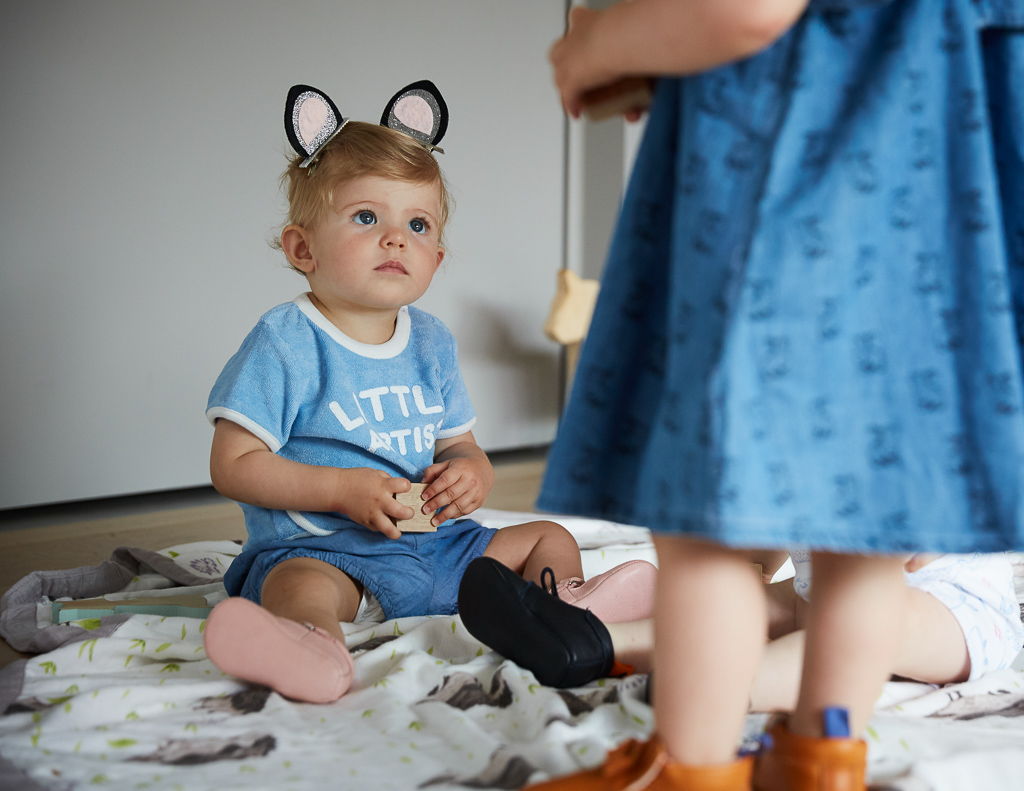 petite fille assise par terre avec chaussons en cuir rose et pyjama bleu