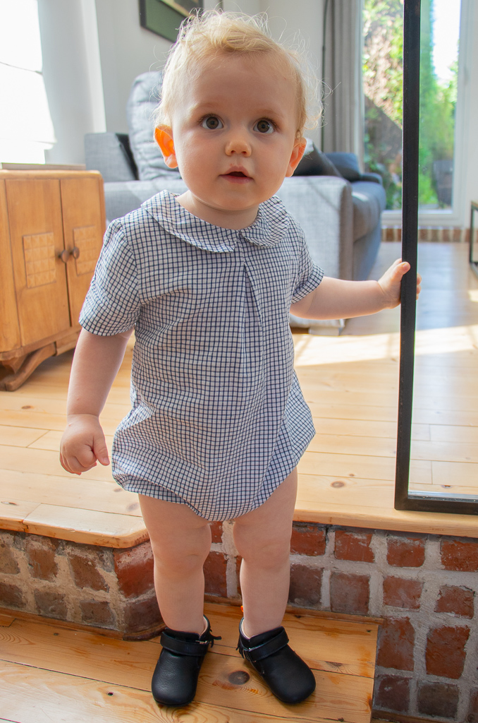 bébé debout sur une marche portant des chaussons en cuir bleu marine