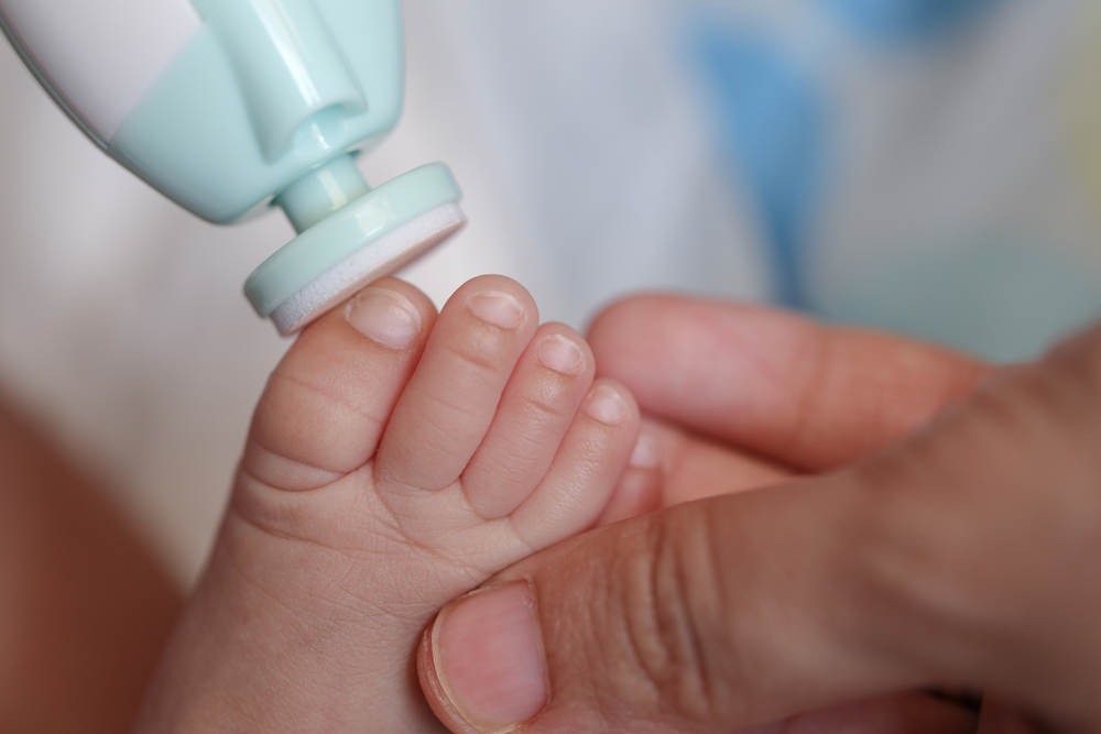 pied d'un bebe qui se fait limer les ongles par une lime à ongle pour bebe