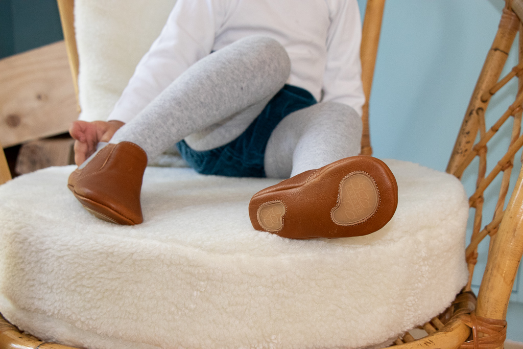 bebe fille assise sur une chaise avec des chaussons en cuir souple anti dérapant