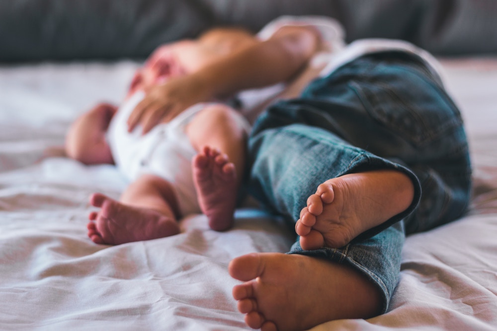 un bébé et un enfant pieds nus allongés à deux dans un lit
