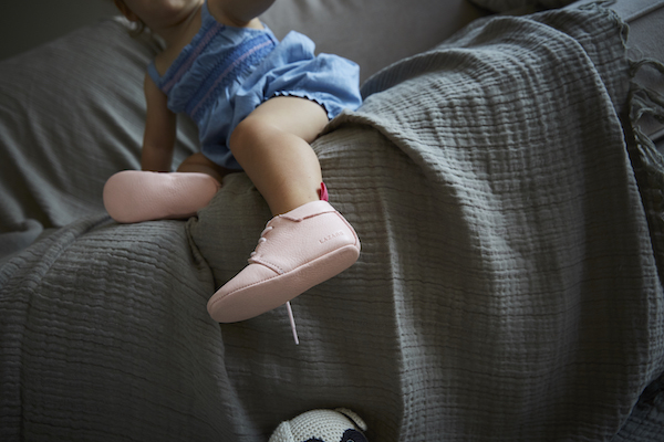 fille assise sur genoux avec chaussons en cuir rose