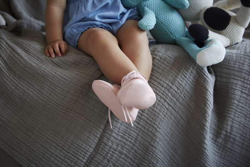 fille assise sur genoux avec chaussons en cuir rose