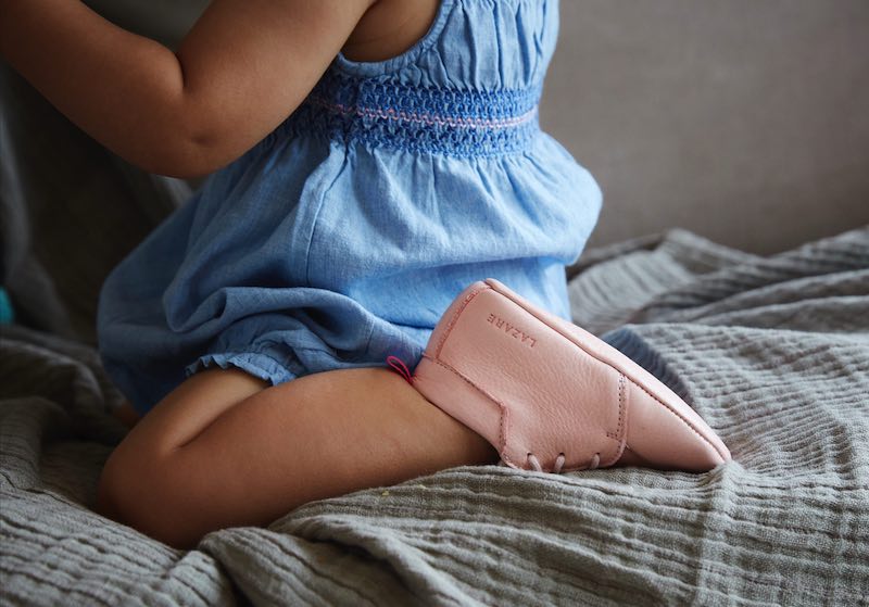 fille assise sur genoux avec chaussons en cuir rose