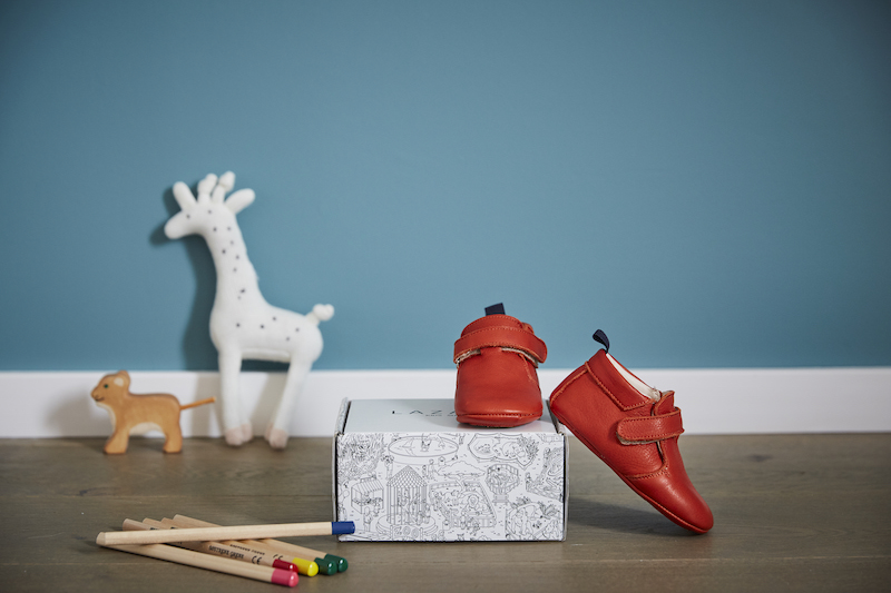 Chaussons bébé Achille rouge en cuir souple sur une boite à chaussures