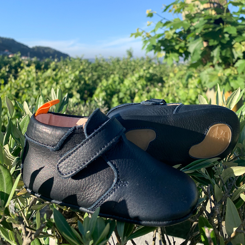 chaussons bébé Achille en cuir souple bleu marine dans de l'herbe