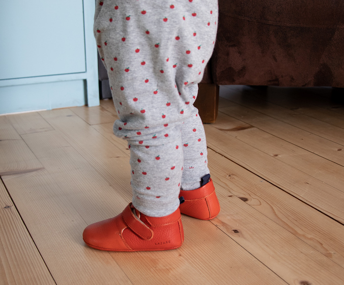 jambes de bébé en pyjama portant des chaussons en cuir souple Achille rouge