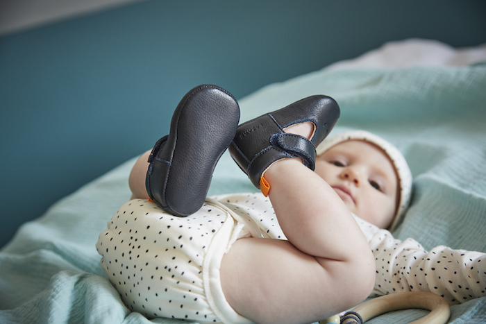 bébé allongé sur le dos portant des chaussons en cuir souple César bleu marine