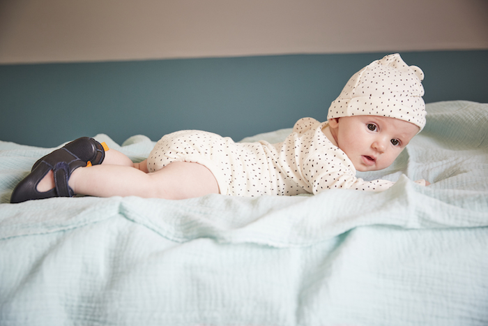 bébé allongé sur le ventre portant des chaussons en cuir souple César bleu marine