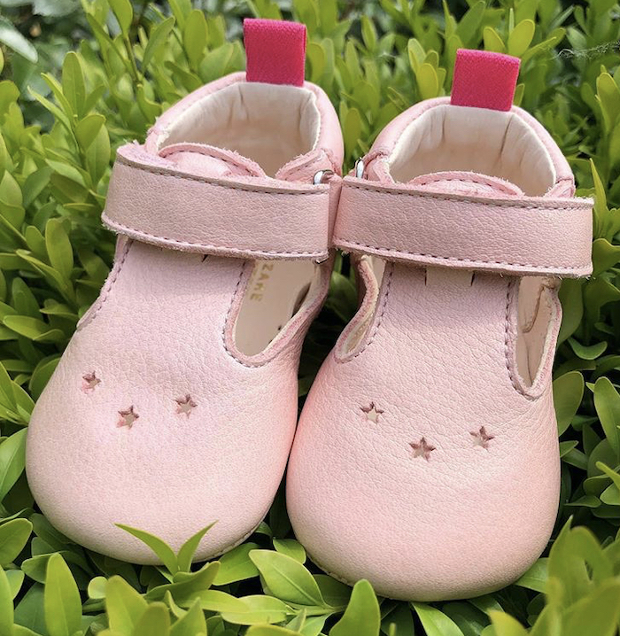 chaussons bébé en cuir souple César rose posés sur herbe