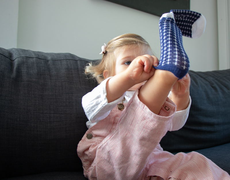 petite fille en train d'enfiler des chaussettes bleu