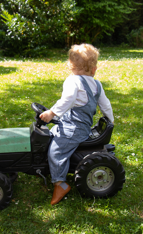 enfant assis sur un jouet tracteur