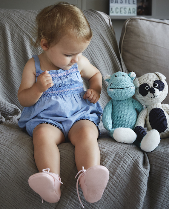 petite fille assise sur un canapé avec des peluches