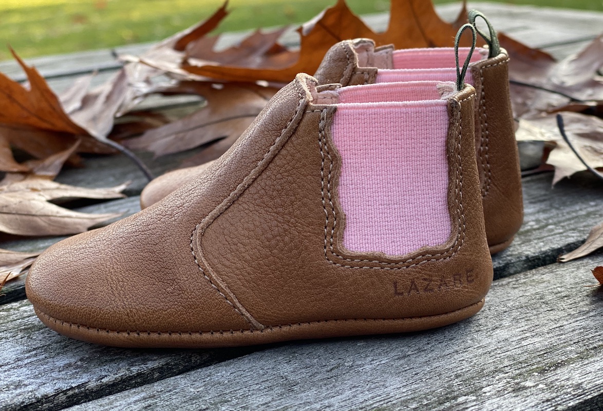 chaussons bébé en cuir souple Oscar marron, élastique rose sur les cotés et languette kaki posés sur des planches de bois