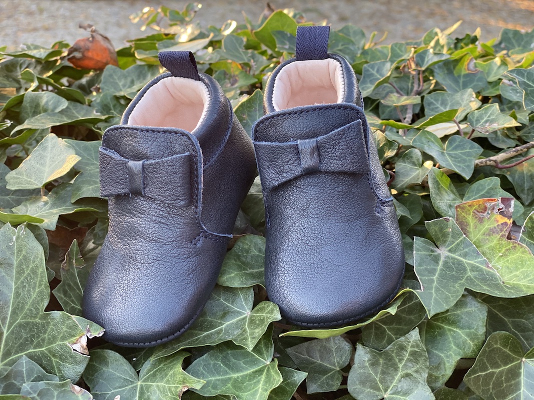 chaussons bébé en cuir souple Arielle bleu marine posés sur des feuilles