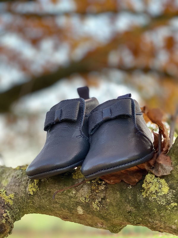 chaussons bébé en cuir souple Arielle bleu marine posés sur des branches