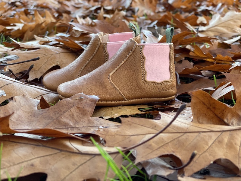 chaussons bébé en cuir souple Oscar marron, élastique rose sur les cotés et languette kaki posés sur des feuilles d'automne