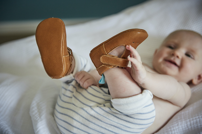 bebe attrape ses pieds sur un lit