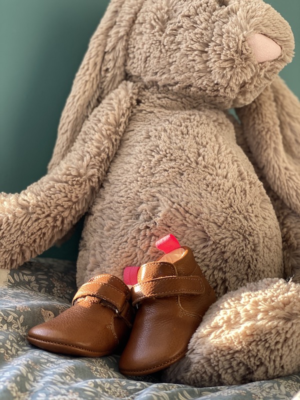 chaussons bébé Suzanne en cuir souple marron posés devant un lapin en peluche