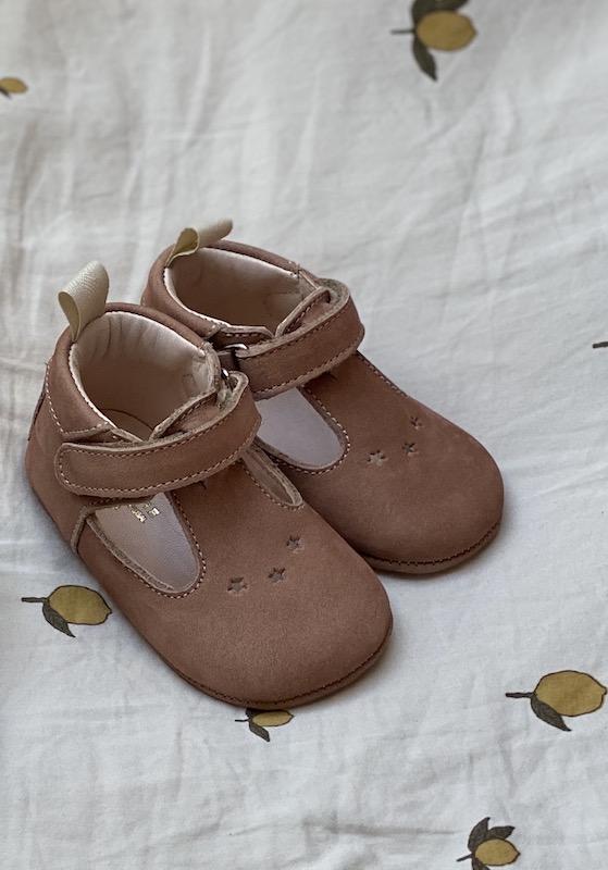 chaussons bébé César en cuir nubuck nue posés sur un drap blanc avec citrons