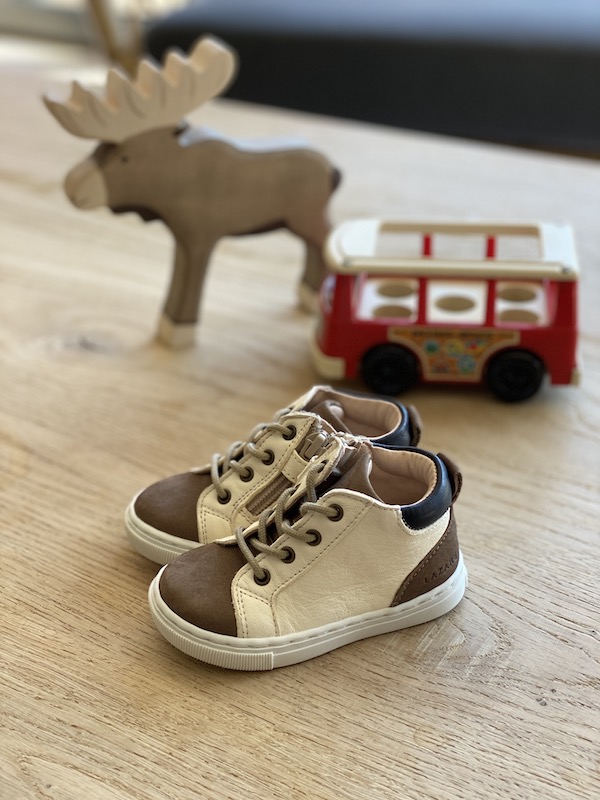 chaussures premiers pas Alegria blanc cassé- bleu marine avec lacets posés sur une table avec jeux en bois en fond